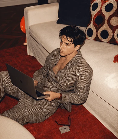 A man with a laptop sitting on a red carpet