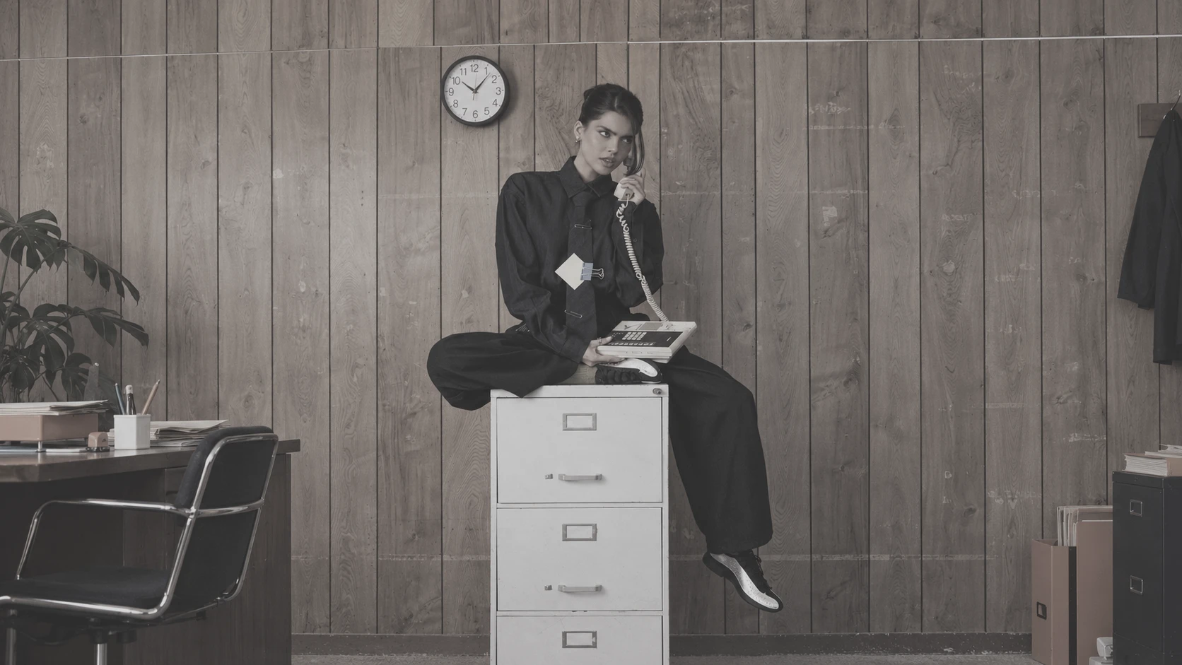A woman on the phone sitting on a filing cabinet